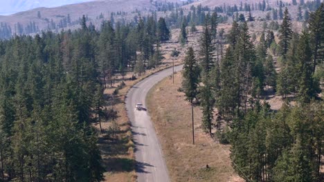 Vista-Aérea-De-Una-Camioneta-Que-Viaja-Por-Una-Carretera-Boscosa-Desierta.