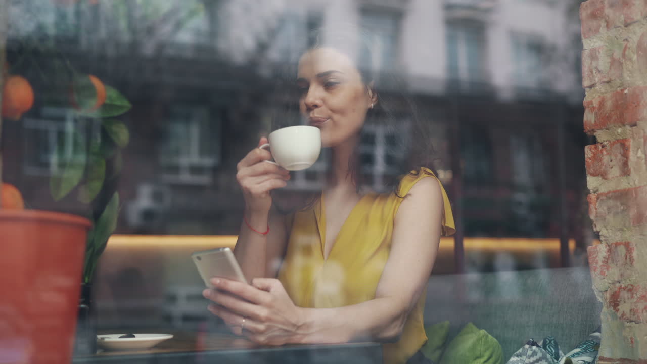 Woman enjoying coffee and using phone in a cafe