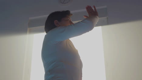 peaceful senior woman practicing tai chi gymnastic in gym