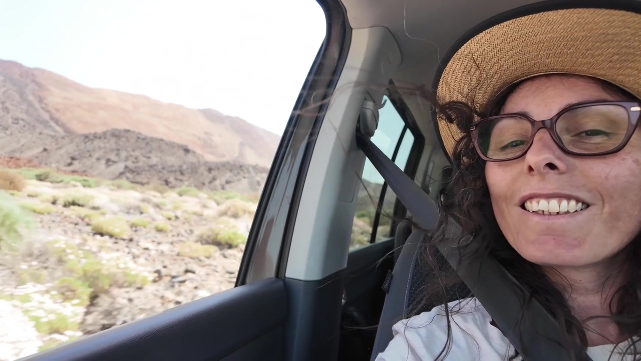 Woman Wearing Hat and Glasses Looking Out Car Window During Road Trip