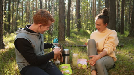 couple enjoying a picnic in the forest with their dog