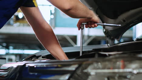 repairman in car service uses wrench