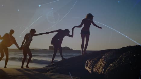 animación de una red de comunicación brillante sobre amigas tomadas de la mano caminando por la playa al atardecer