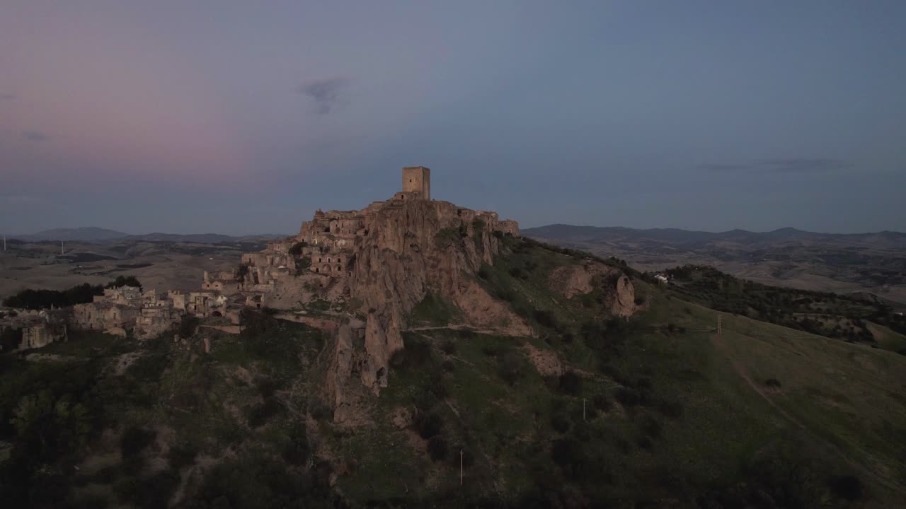 drone volando en gran movimiento circular alrededor de las ruinas de craco en la cima de una colina en el sur de italia en la luz de la mañana muy temprano en 4k