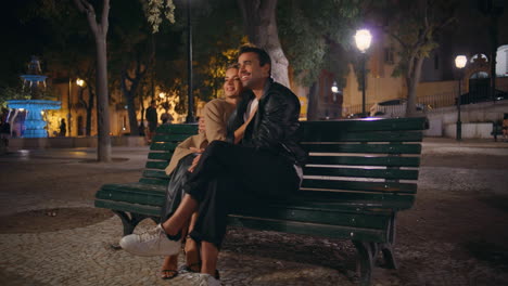 affectionate couple sitting park cuddling in evening date. happy spouses resting