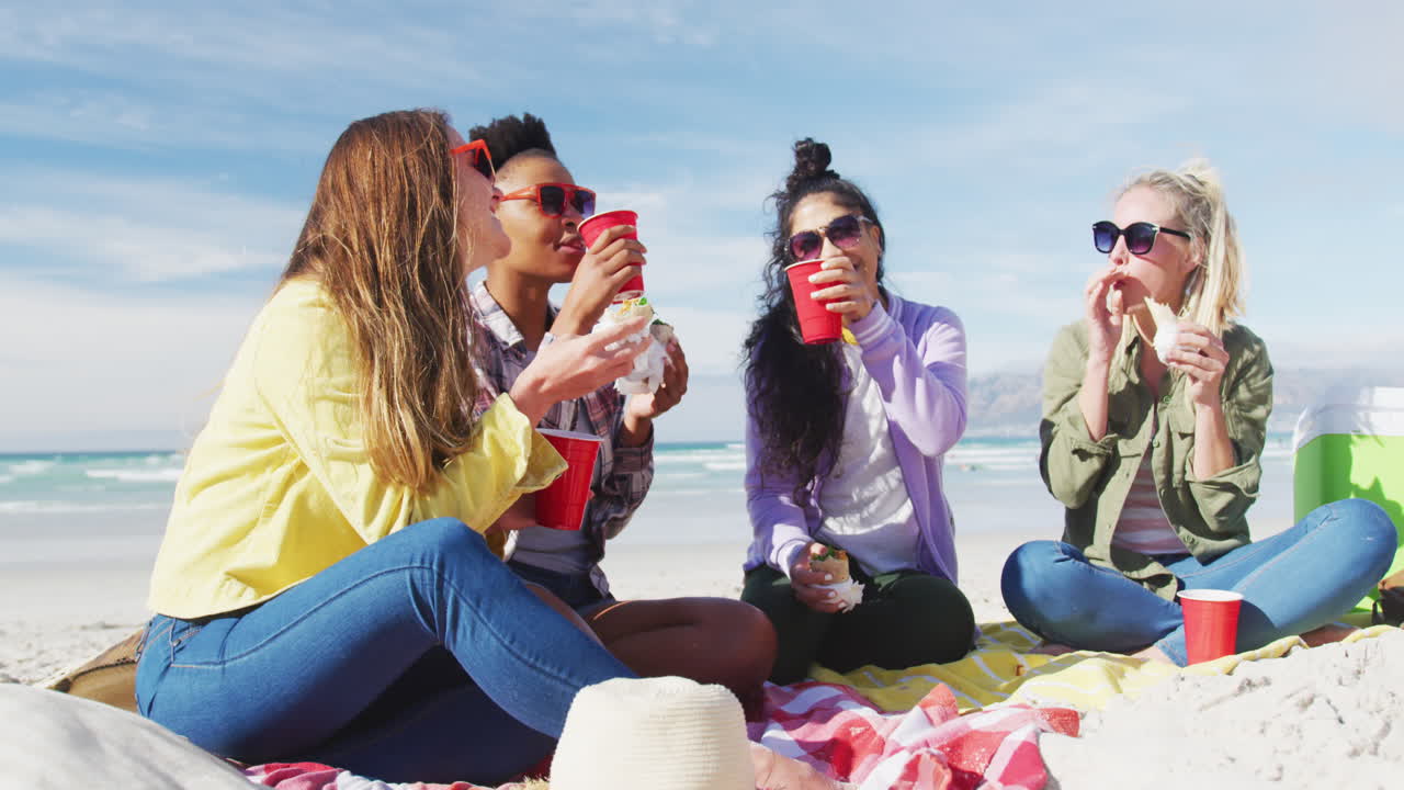 해변에서 피크닉을 하는 다양한 여성 친구들의 행복한 그룹