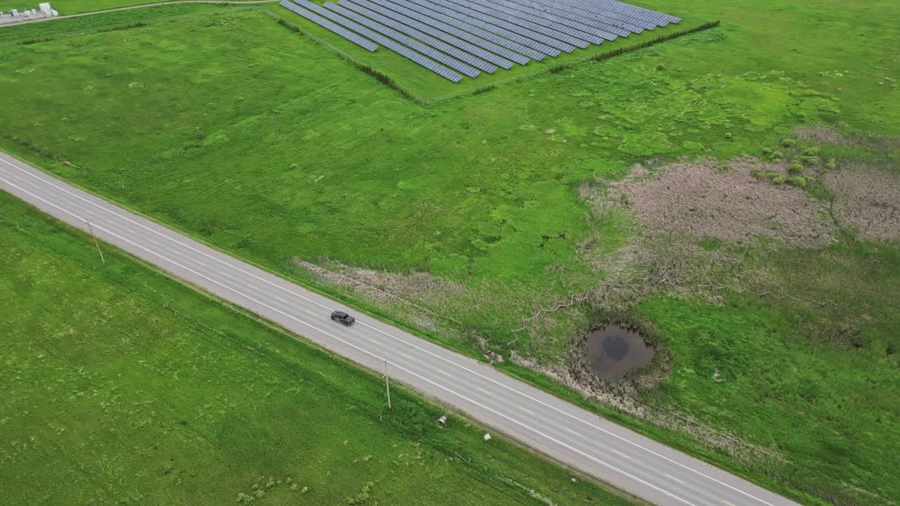 coche conduciendo en la carretera que pasa por la central eléctrica de paneles solares