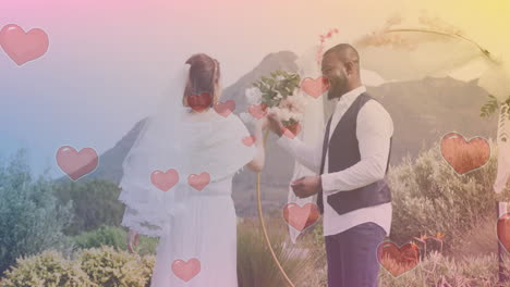 hearts animation over couple exchanging vows in outdoor wedding ceremony