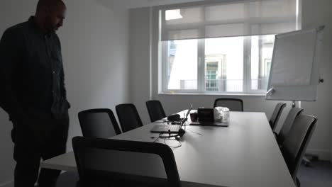 impatient businessman pacing up and down in meeting room looking at laptop