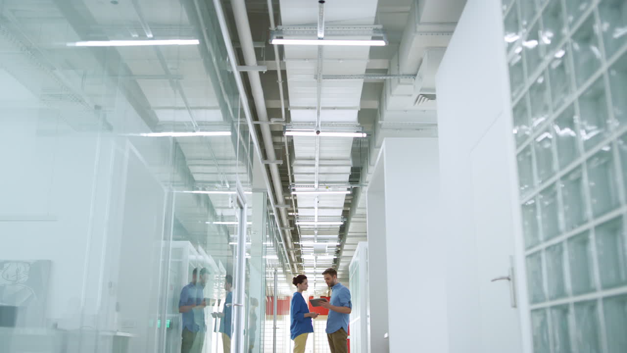jóvenes empleados buscando tabletas en oficinas modernas. gente de negocios hablando.