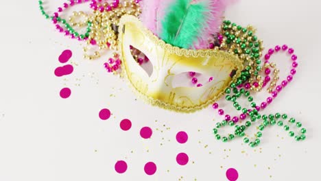 Video-of-masquerade-mask-with-feathers,-mardi-gras-beads-and-confetti-on-white-background