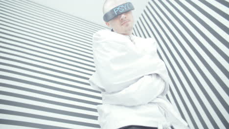 man in restraints with vr glasses in a striped room