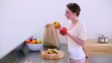 bonito modelo de pie en la cocina tomando pimientos de la bolsa de comestibles