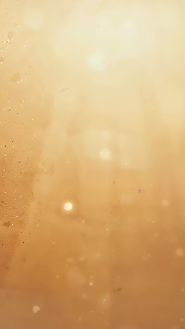 Vertical video: Pulsing golden column nudging dust drifting in close-up with rays, revealing bokeh