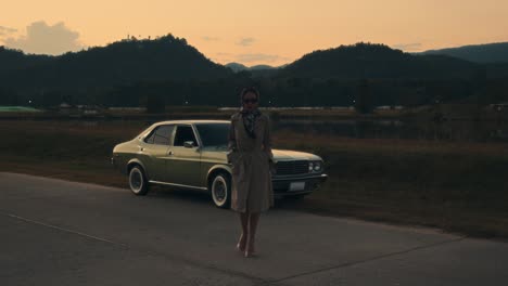 vintage woman by classic car at sunset