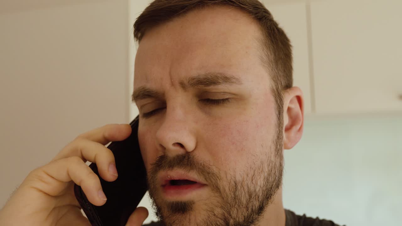 Uomo che cammina per il suo appartamento mentre parla al suo smartphone durante una telefonata