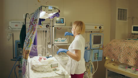 nurse caring for newborn in incubator