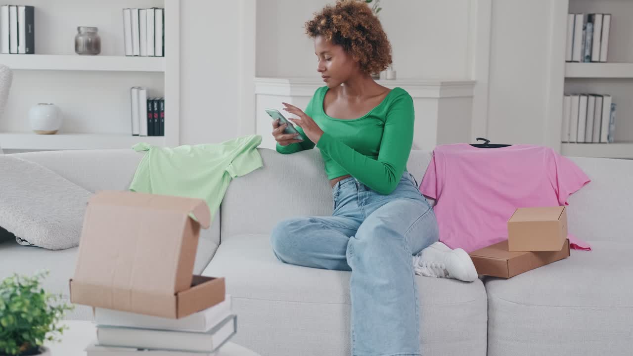 Young african american woman ordering clothes through mobile apps on phone