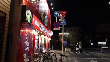 pedestrians and cyclists passing by a ramen shop