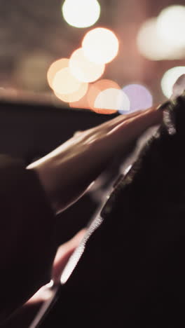 vista en primera persona de una mano golpeando la bocina de un coche en la noche. la escena presenta luces borrosas de la ciudad en el fondo