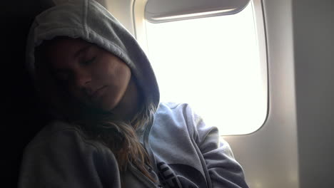 Young-woman-sitting-by-the-window-in-a-plane-asleep