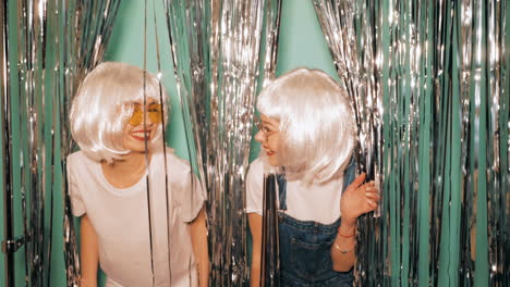 two friends having fun behind silver tinsel