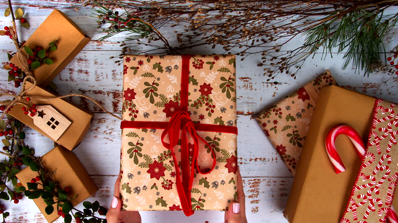 Beautifully wrapped Christmas gift with festive red ribbon and natural décor, placed among holiday packages. Perfect for seasonal displays, gift ideas, and festive celebrations. Flat Lay.