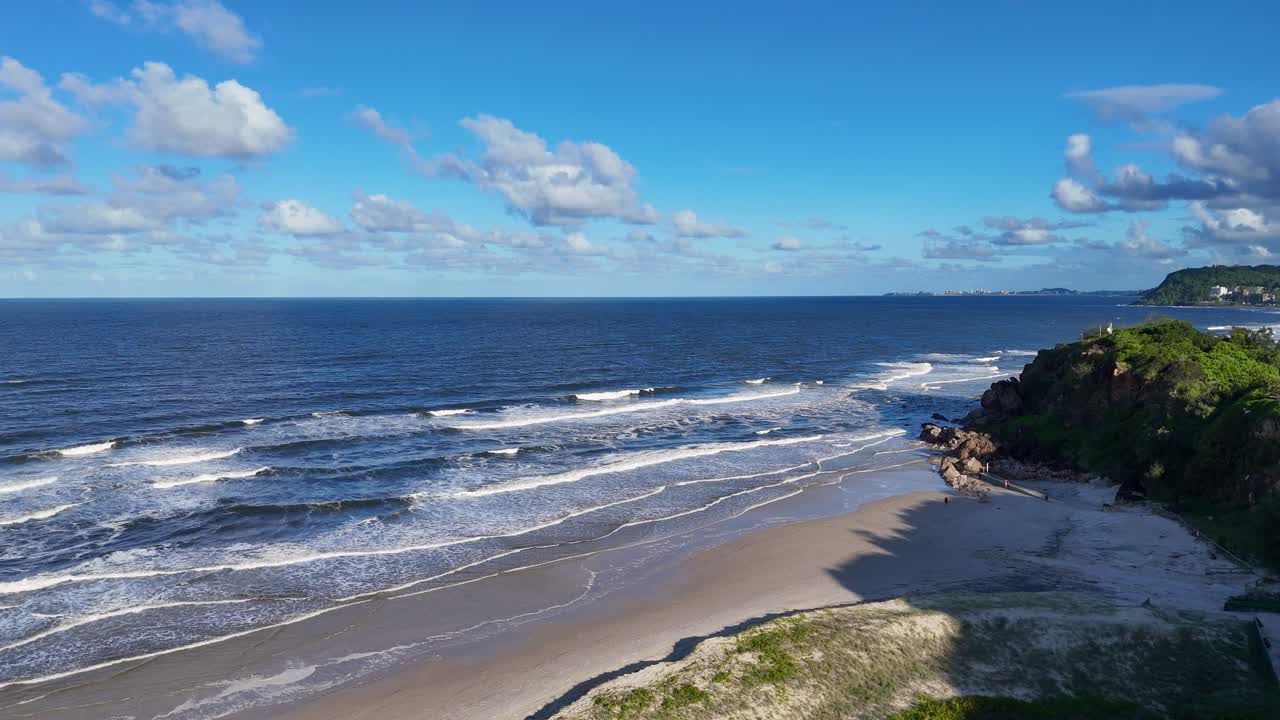 Aerial view of waves crashing against cliffs on a sunny day at Gold Coast, Australia. Dynamic ocean scene with clear skies