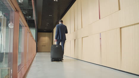 an unrecognizable businessman walks backwards with a trolley 2