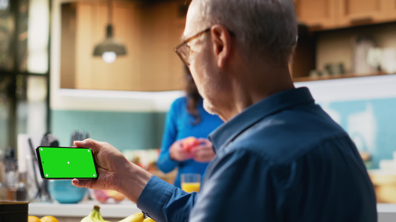 Horizontal green screen on mobile phone with pensioner at the breakfast table