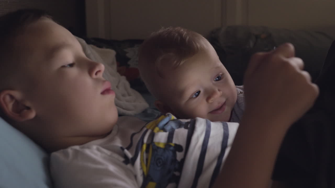 брат на планшете с младшей сестрой