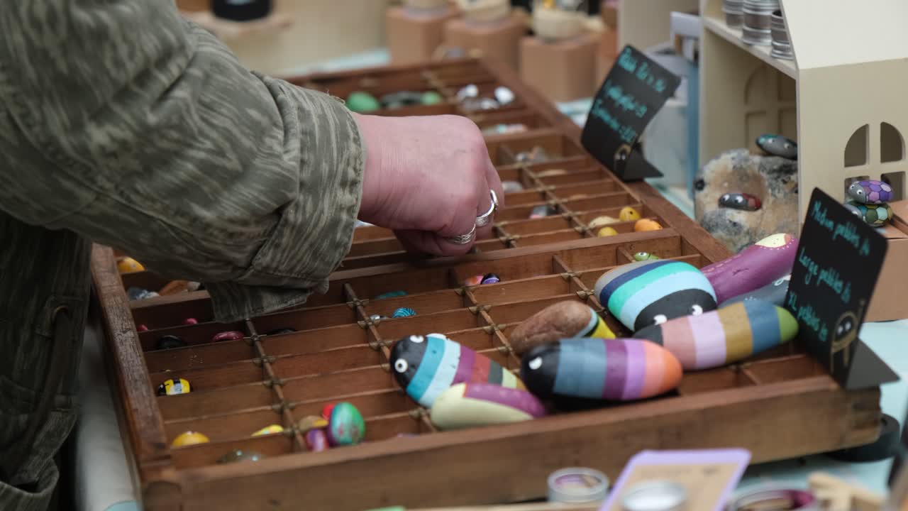 Woman choosing handmade crafted jewellery stones at local market stall.