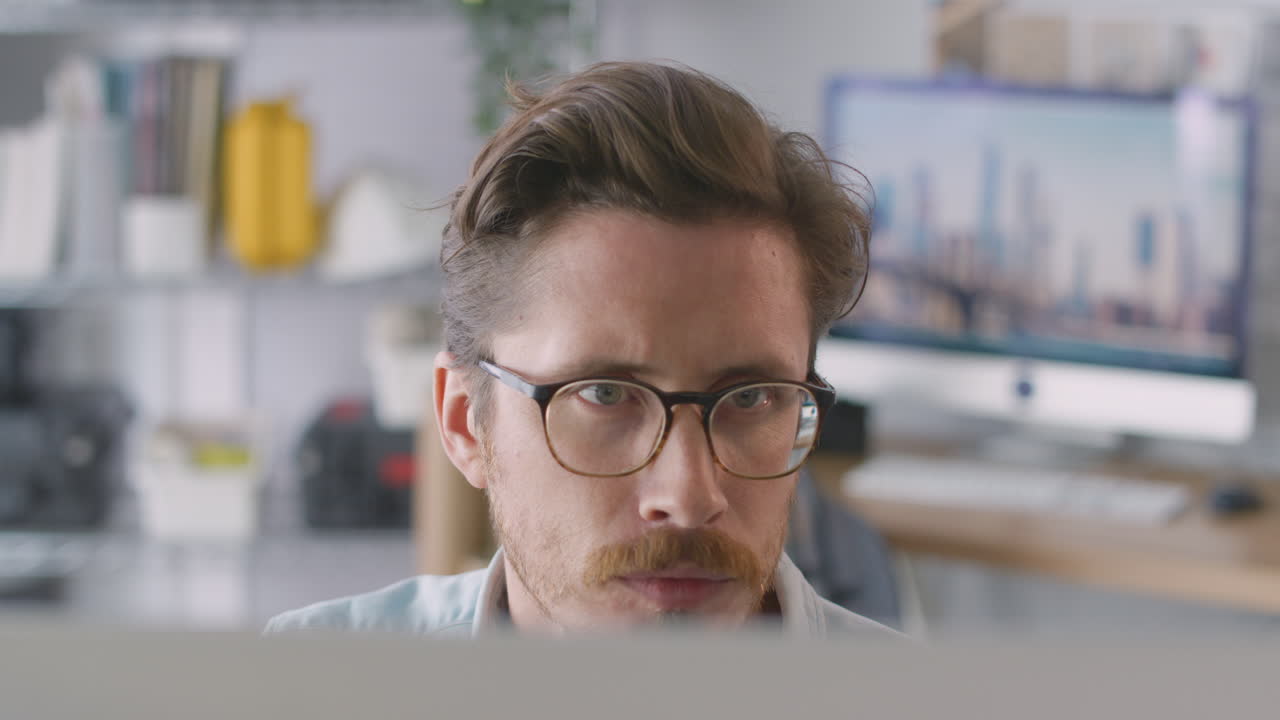 primer plano de un arquitecto masculino en la oficina trabajando en una computadora de escritorio vista desde detrás de la pantalla