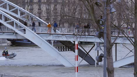 pedestrians walking over flooded bridge in paris