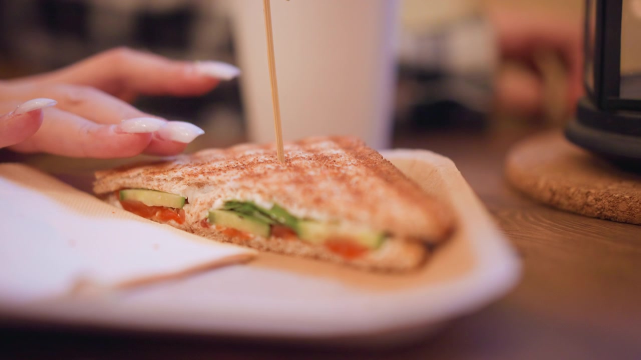 Primo piano di un toast con pomodoro, cetriolo e verdure a foglia visibili su pane integrale. La scena include un'illuminazione soffusa che evidenzia i dettagli della texture come i motivi della crosta.