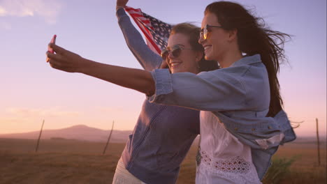 hermosas amigas tomando selfies en un viaje por carretera al atardecer con un coche antiguo