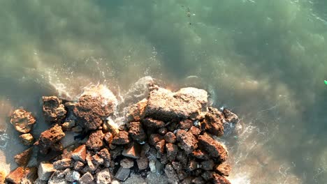 Albania,-foamy-waves-crashing-against-rocks-on-the-beach