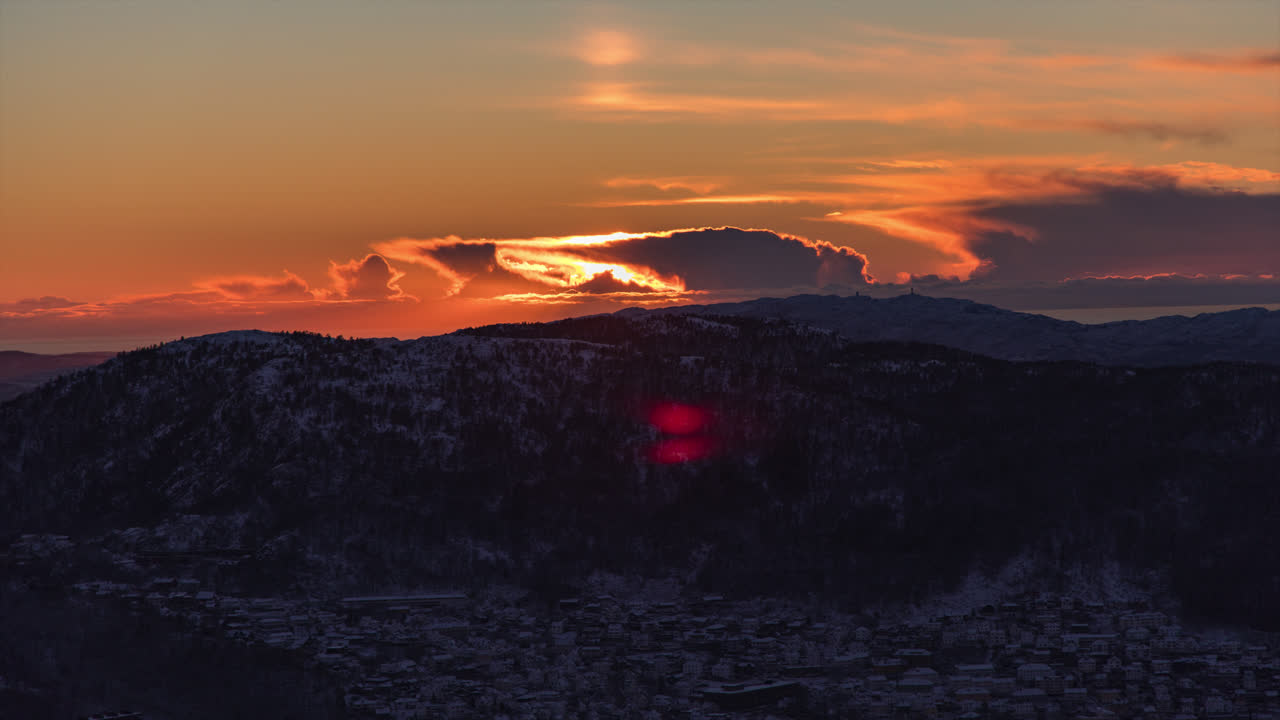 hermosa puesta de sol detrás de montañas nevadas cerca de la ciudad