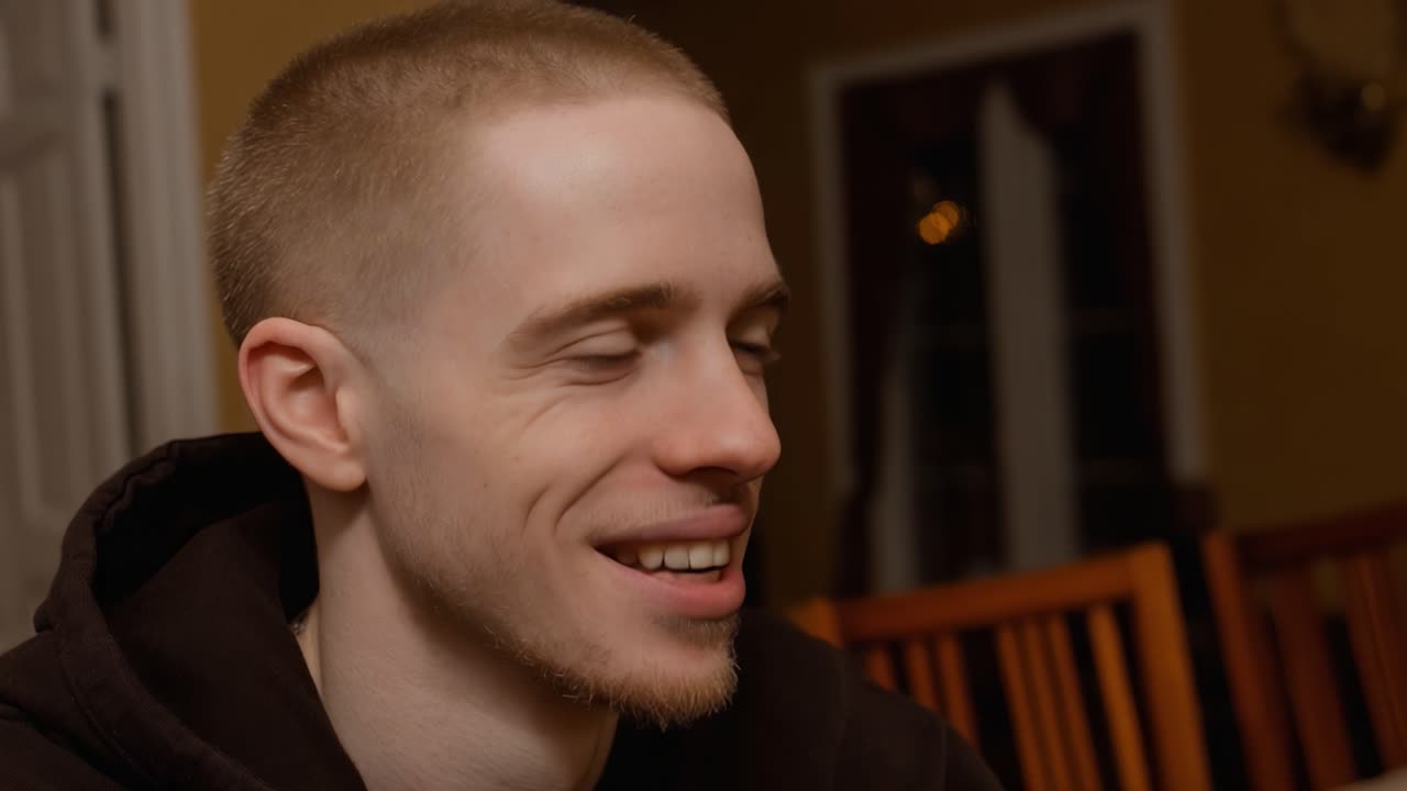 A Joyful Moment: Capturing a Gleeful Expression on a Young Man's Face in a Cozy Indoor Setting with Warm Lighting