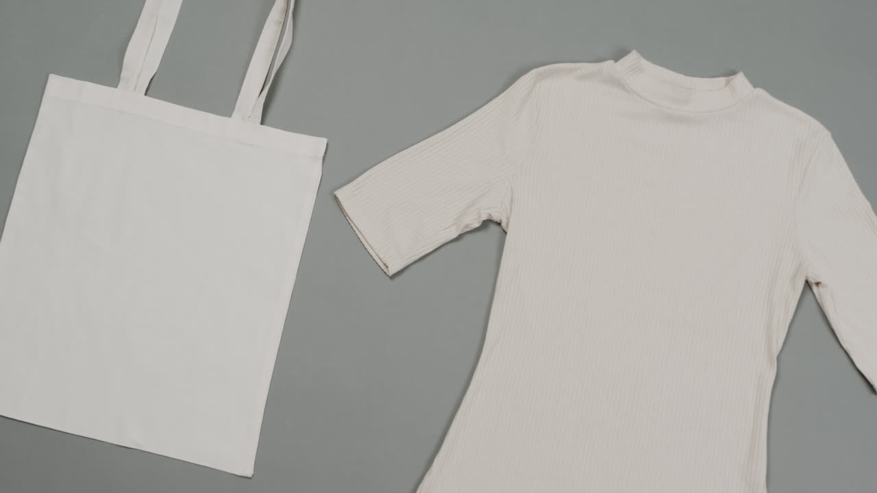 회색 배경에 색 가방과 티셔츠의 클로즈업, 복사 공간, 느린 동작