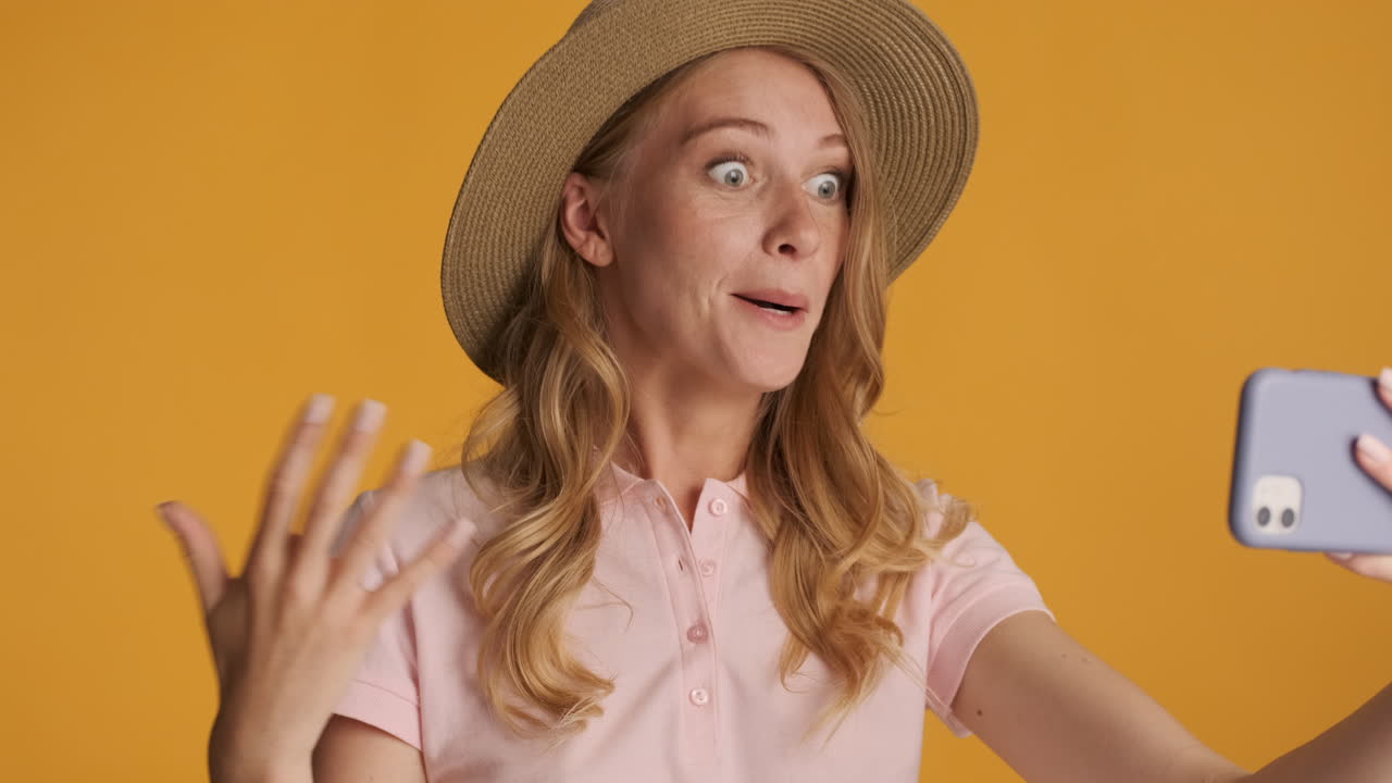 mujer caucásica con un sombrero haciendo una llamada de video en el teléfono inteligente.