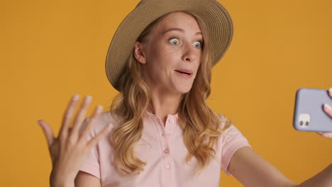 mujer caucásica con un sombrero haciendo una llamada de video en el teléfono inteligente.