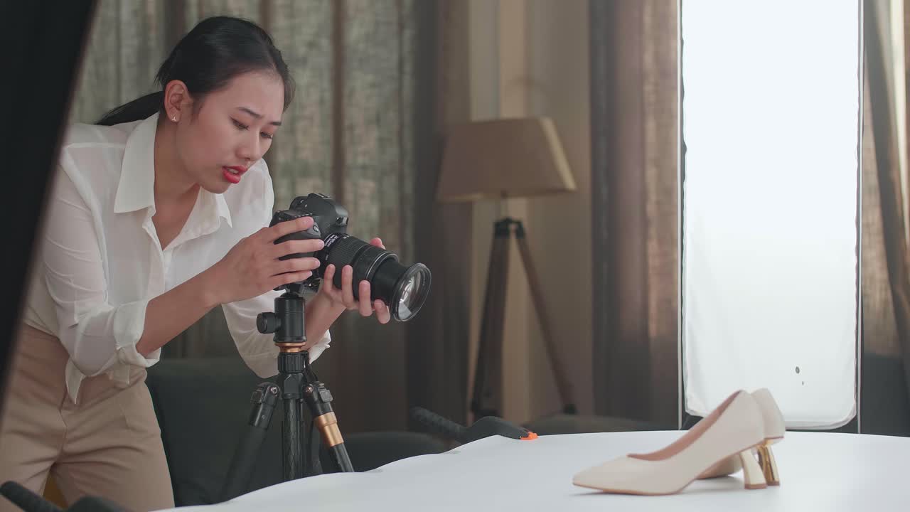 아시아 여성 사진작가는 가정 스튜디오에서 사진을 찍는 동안 지표손가락을 들어 올립니다.