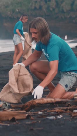 young caring caucasian man and woman collect waste thrown up by waves on beach