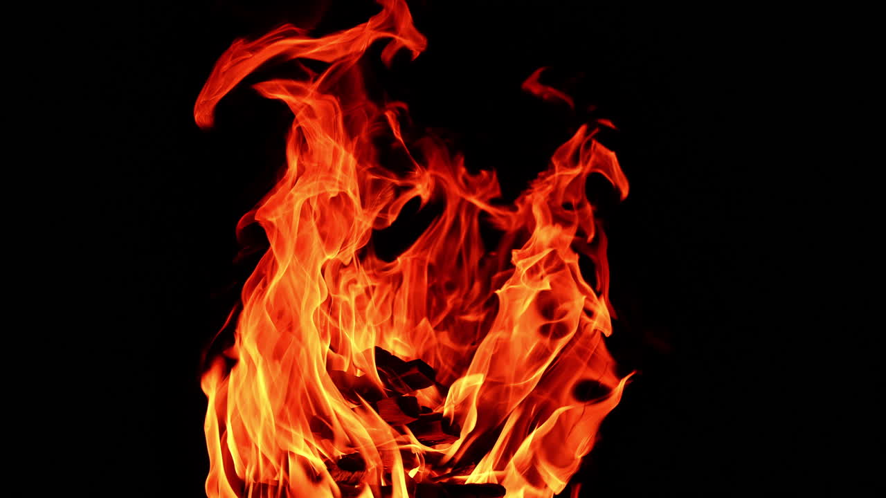 Chops of wood piled in a stack burn in the campfire. Isolated view of bonfire burning at night.