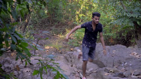 niño corriendo por la jungla asustado en pantalones cortos rayos de sol a través de rocas rápido