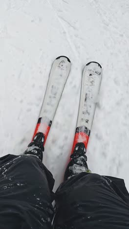 Vertikaler-Video-POV-Skifahrer,-Der-Einen-Schneebedeckten-Hang-Hinunterfährt-Und-Skier-Hinunterschaut