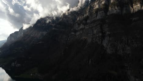 Tiro-Bajo-De-Montañas-Rocosas-Y-Nubes-En-La-Superficie-Del-Lago-Walensee-Unterterzen-En-Suiza