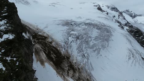 Der-Erhöhte-Blick-Zeigt-Die-Weite-Fläche-Des-Hohen-Tauern-Gletschers-Mit-Seinen-Gewundenen-Eisströmen,-Eingebettet-Zwischen-Schroffen-Gipfeln,-Unter-Einem-Wolkenverhangenen-Himmel