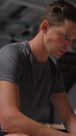 vertical video portrait of determined male athlete sport training in gym sitting and concentrating in changing room with focused expression 5